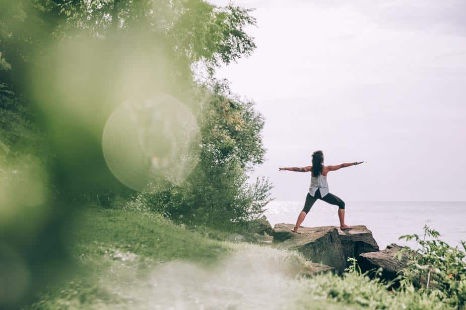 A woman does yoga on a path by the water