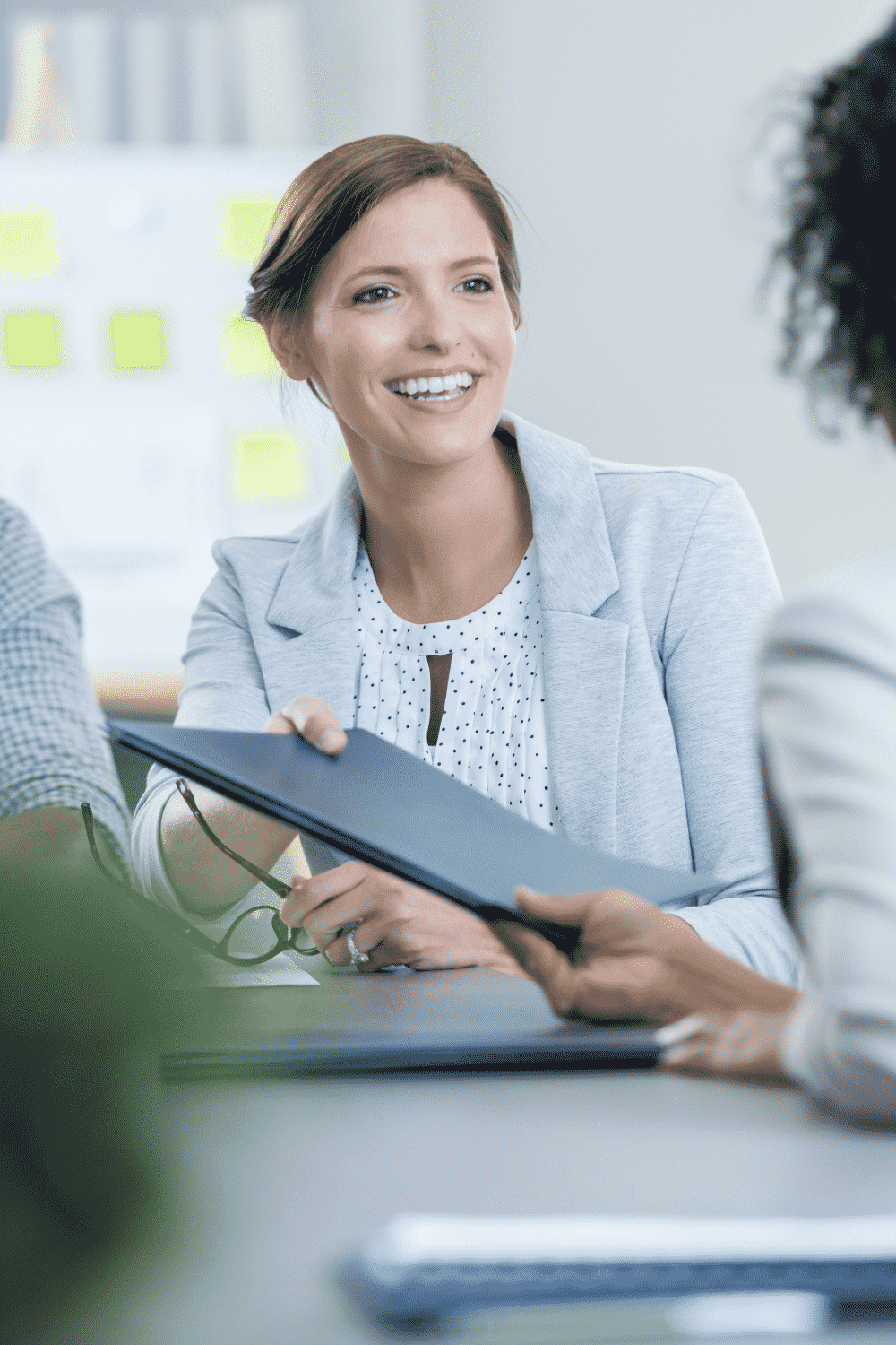A woman hands her portfolio to her boss after asking for a raise